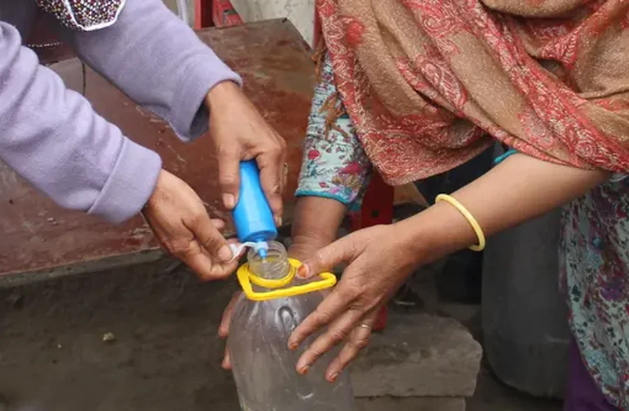 A resident fills a bottle through the filter during a field session outside Lahore.